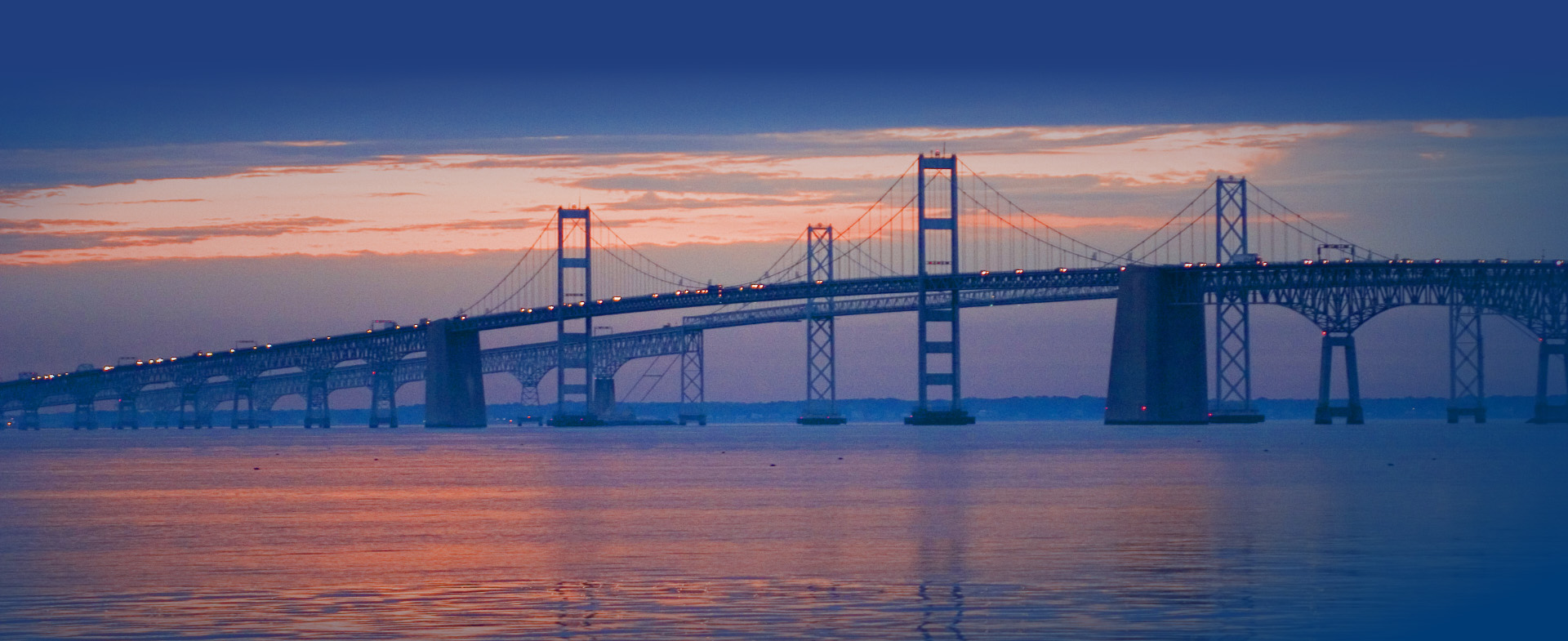 The Chesapeake Bay Bridge at sunset backed with an orange sky.